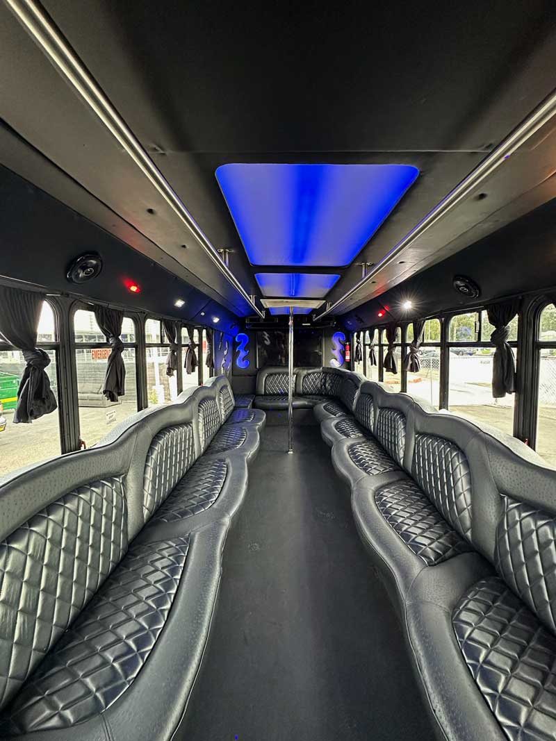 King XIII party bus interior with black diamond quilted leather seating and blue ceiling panel lighting