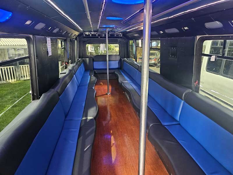 Kloud 9 party bus interior with blue leather seating, hardwood floors, and LED accent lighting